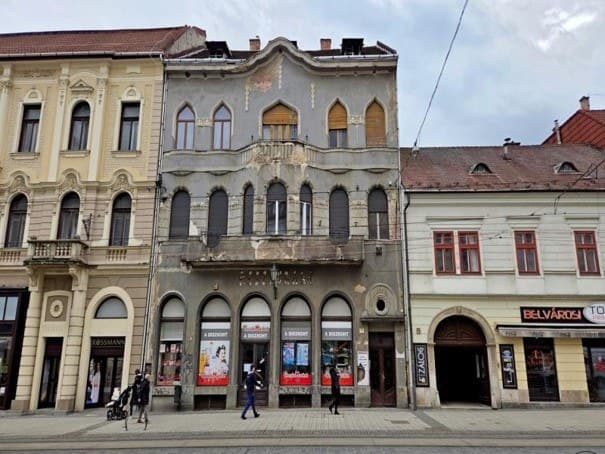 Ívelt ablakos, felújításra váró historizáló belvárosi épület homlokzata