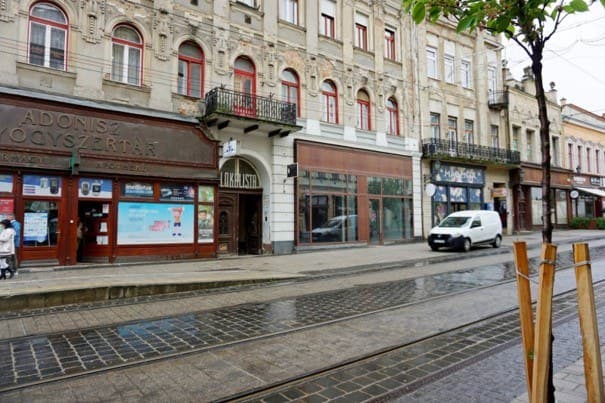 Belvárosi épület földszinti üzlethelyiségekkel, villamossínekkel az utcán