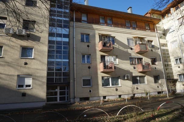 Négyemeletes társasház erkélyekkel, zöld környezetben